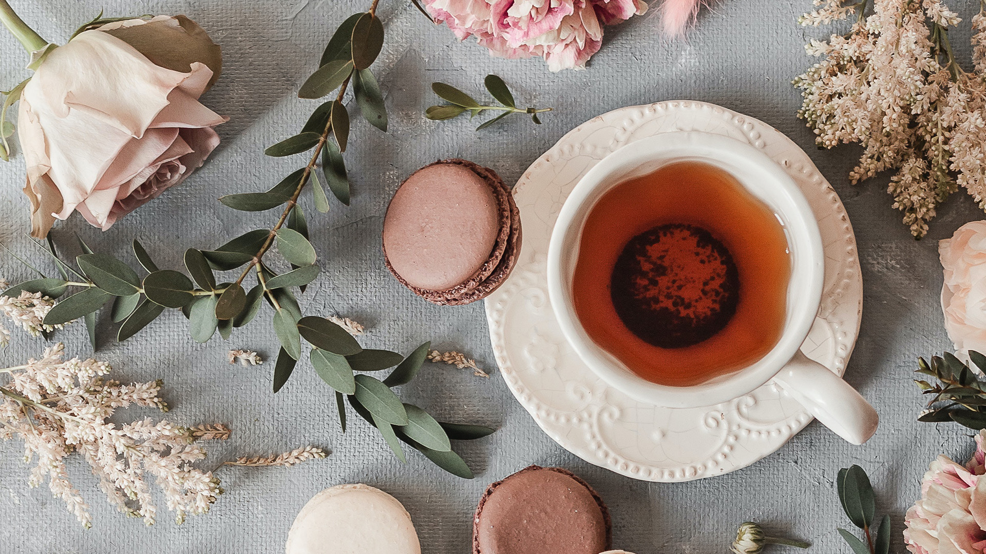 Teetasse mit Gebäck und Blumen auf einem Tisch