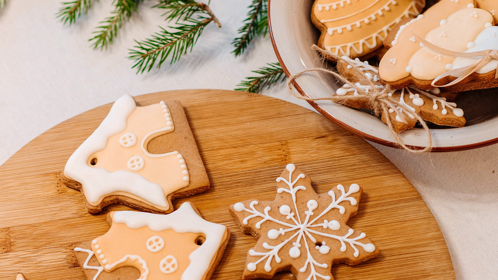 Weihnachtsgebäck auf einem Brettchen und einer Schale, dekoriert mit einem Tannenzweig