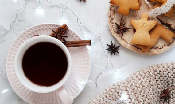 weihnachtlich gedeckter Kaffeetisch mit Dekoration, weißer Decke, Plätzchen und Anis und Zimt